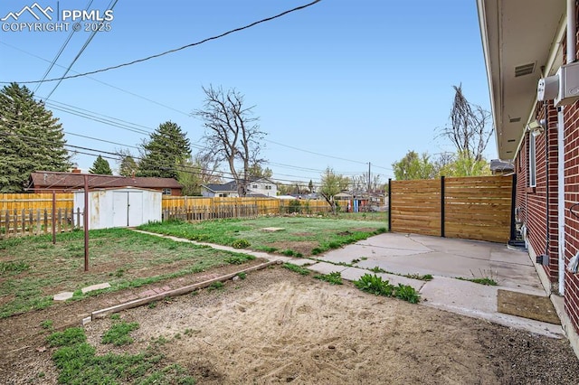 view of yard with an outdoor structure, a fenced backyard, a patio area, and a shed