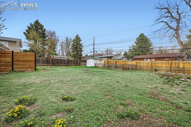 view of yard with a fenced backyard, an outbuilding, and a storage shed