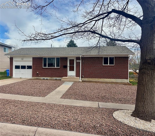 single story home featuring brick siding, driveway, a shingled roof, and a garage