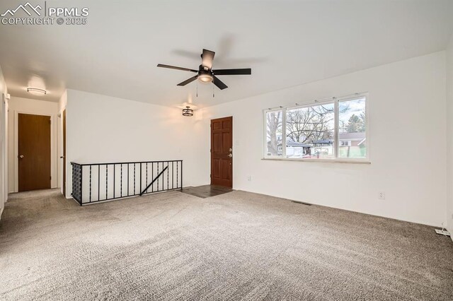 empty room featuring visible vents, carpet flooring, and ceiling fan