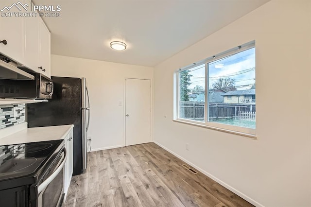kitchen with light wood-style floors, stainless steel range with electric stovetop, white cabinets, and tasteful backsplash