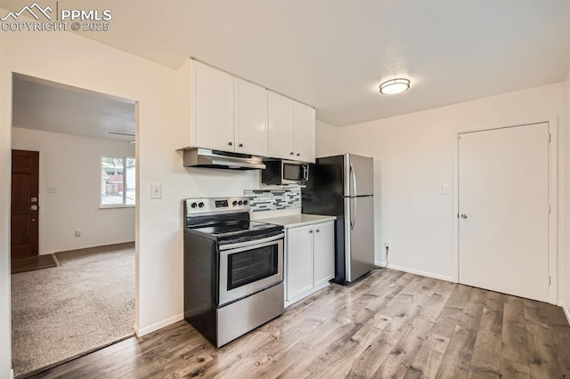 kitchen with white cabinets, appliances with stainless steel finishes, backsplash, light wood-type flooring, and under cabinet range hood