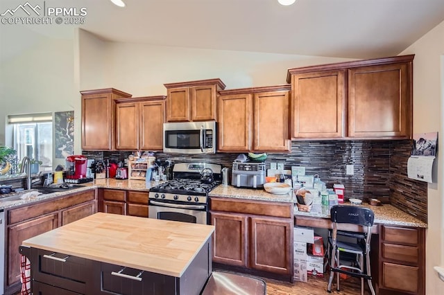 6041 Leon Young Dr, Colorado Springs, CO 80924 - kitchen with appliances with stainless steel finishes, a sink, butcher block countertops, tasteful backsplash, and high vaulted ceiling