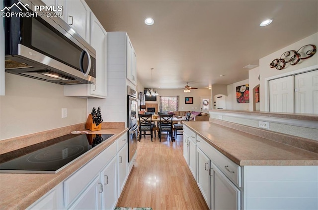 kitchen with a ceiling fan, stainless steel appliances, light wood-type flooring, and white cabinetry