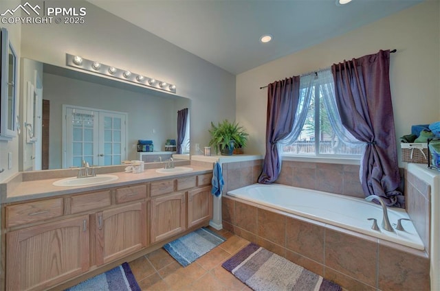 bathroom with double vanity, tile patterned flooring, a sink, and a bath