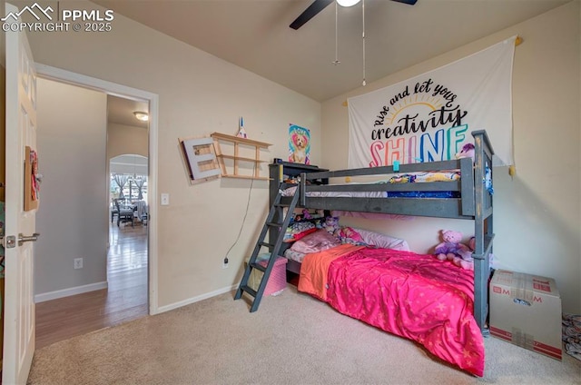 bedroom featuring carpet floors, baseboards, arched walkways, and ceiling fan
