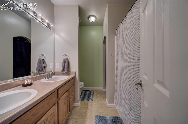 full bath with double vanity, a sink, toilet, and a shower with curtain