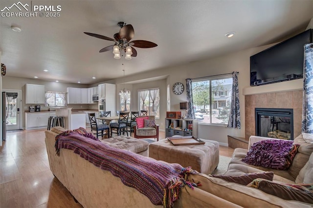 living room with light wood-style floors, baseboards, ceiling fan, recessed lighting, and a tiled fireplace