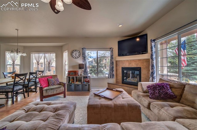 living room featuring ceiling fan with notable chandelier, a healthy amount of sunlight, and a fireplace