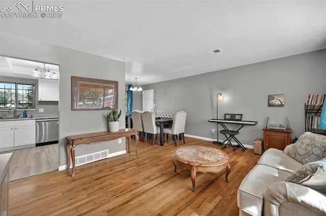 806 N Chelton Rd, Colorado Springs, CO 80909 - living area featuring a chandelier, light wood-type flooring, and baseboards