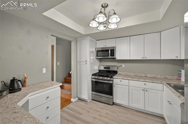 806 N Chelton Rd, Colorado Springs, CO 80909 - kitchen with stainless steel appliances, a raised ceiling, white cabinetry, and a chandelier