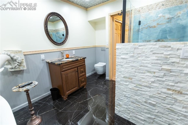bathroom featuring a wainscoted wall, ornamental molding, a stall shower, and toilet