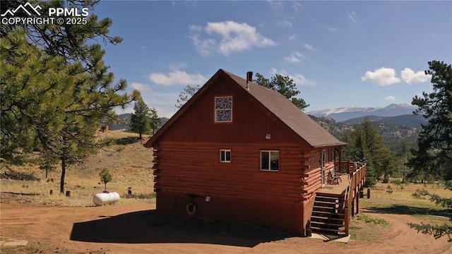 view of side of home featuring a deck with mountain view, log siding, and stairs