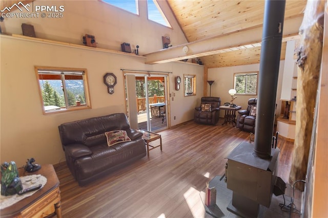 living area with wood ceiling, a wealth of natural light, a wood stove, and wood finished floors