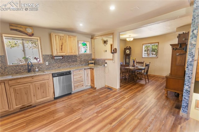 kitchen featuring decorative backsplash, stainless steel dishwasher, a sink, light wood finished floors, and light brown cabinets