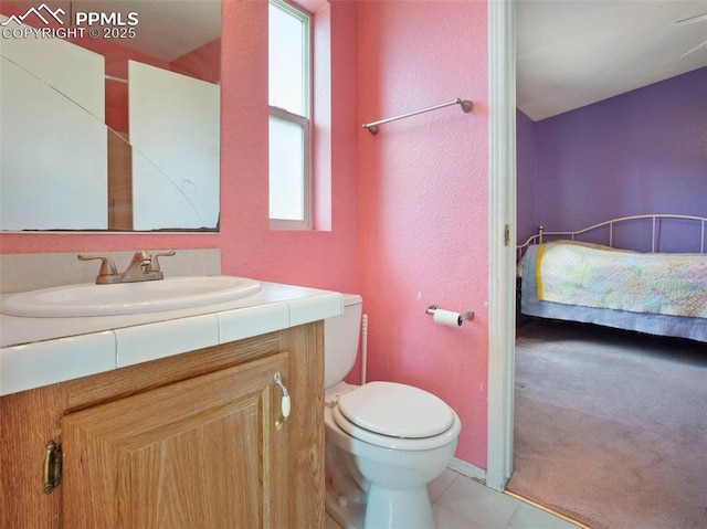 bathroom featuring vanity, tile patterned flooring, a textured wall, and toilet
