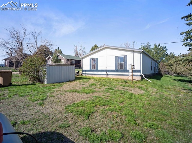 back of house featuring an outdoor structure, a yard, and a shed