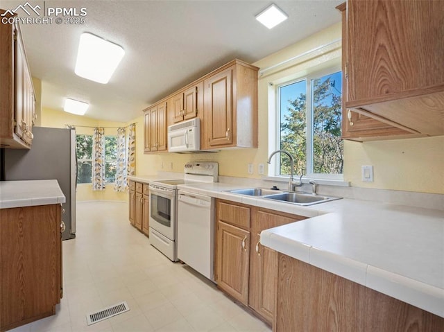 kitchen featuring a sink, light countertops, white appliances, and visible vents