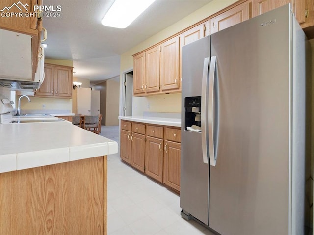 kitchen featuring stainless steel fridge, a sink, light brown cabinets, light countertops, and light floors