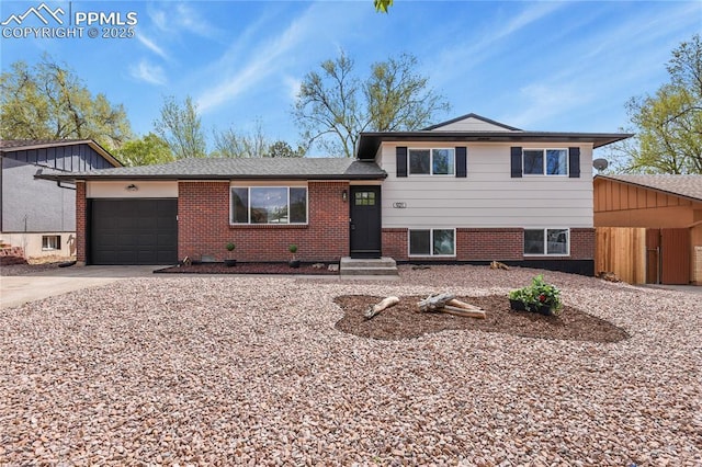tri-level home with concrete driveway, brick siding, and a garage
