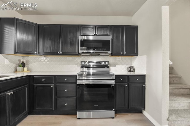 kitchen featuring appliances with stainless steel finishes, light countertops, baseboards, light wood-type flooring, and backsplash