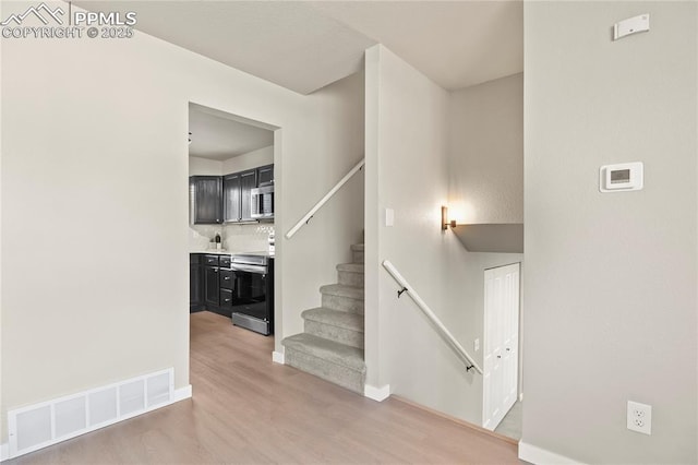 stairway with baseboards, visible vents, and wood finished floors