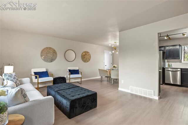 921 Holmes Dr, Colorado Springs, CO 80909 - living room with baseboards, visible vents, and light wood-style flooring