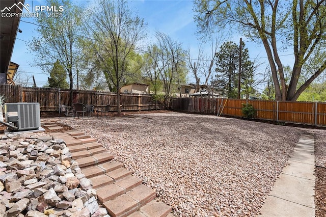 view of yard featuring central AC, a fenced backyard, and a patio area