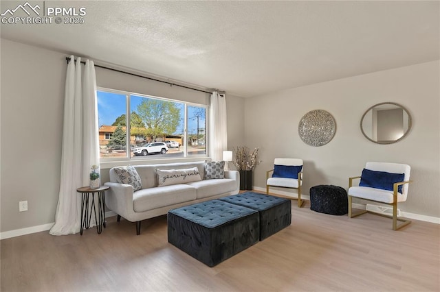 living area with a textured ceiling, baseboards, and wood finished floors