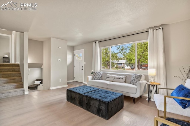 living room featuring baseboards, wood finished floors, and stairway