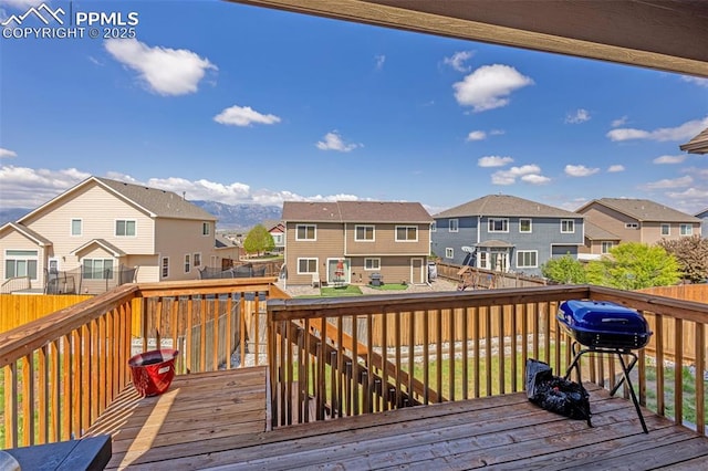 wooden deck with a residential view, a grill, and fence