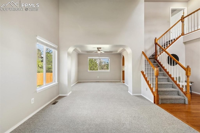7665 Calloway Ct, Colorado Springs, CO 80919 - unfurnished living room with arched walkways, a high ceiling, carpet floors, and stairway