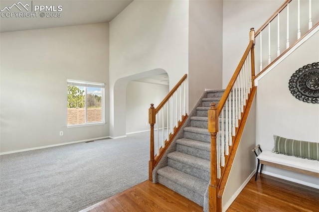 7665 Calloway Ct, Colorado Springs, CO 80919 - stairway featuring a towering ceiling, arched walkways, baseboards, and wood finished floors