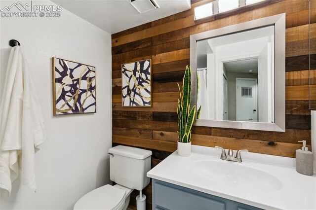 8365 Pepperridge Dr, Colorado Springs, CO 80920 - bathroom featuring wooden walls, vanity, and toilet