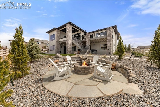 back of property featuring a fire pit, fence, stone siding, a patio, and stairway