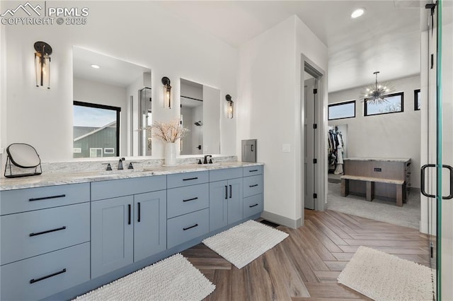 full bathroom featuring double vanity, a sink, baseboards, a notable chandelier, and recessed lighting