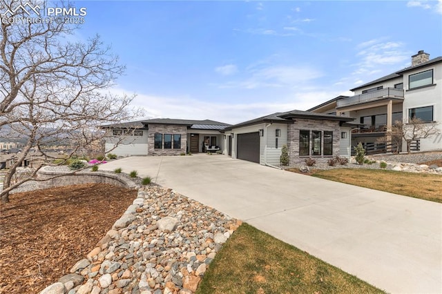 prairie-style home featuring an attached garage, concrete driveway, and stone siding