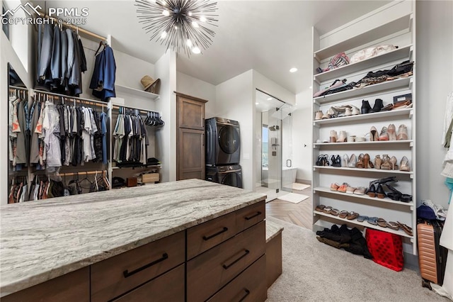 walk in closet featuring an inviting chandelier and stacked washer and clothes dryer
