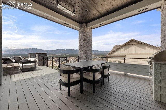 wooden deck featuring a fire pit, a mountain view, and outdoor dining space
