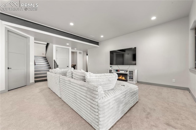 living room featuring recessed lighting, a warm lit fireplace, light carpet, and stairway