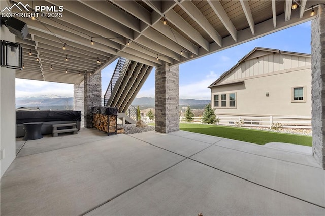 view of patio with stairs, a hot tub, and a mountain view