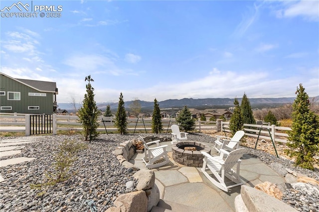view of patio with fence, a mountain view, and a fire pit