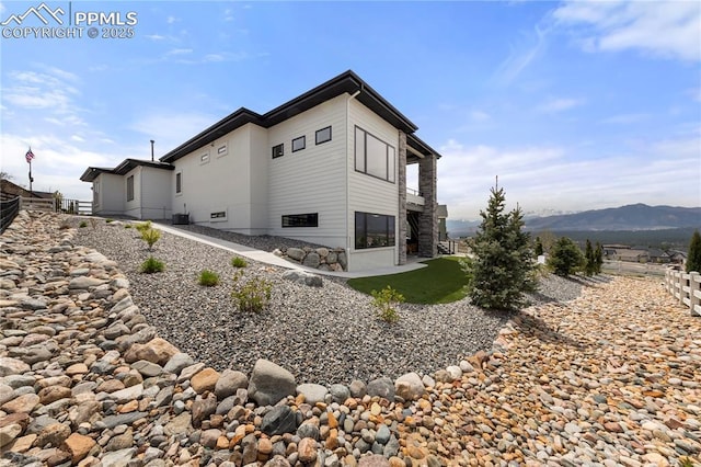 view of side of property with fence and a mountain view
