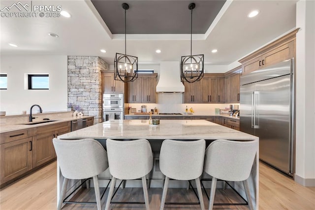 kitchen featuring a sink, appliances with stainless steel finishes, a breakfast bar, and custom range hood