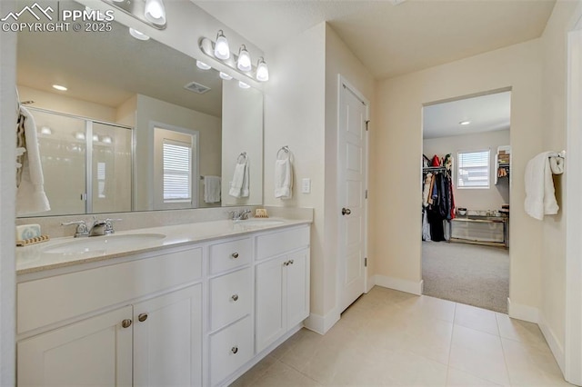 9773 Marble Canyon Way, Peyton, CO 80831 - full bath with double vanity, a stall shower, baseboards, tile patterned flooring, and a walk in closet
