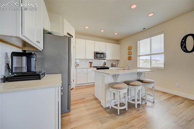 9773 Marble Canyon Way, Peyton, CO 80831 - kitchen with stainless steel microwave, a sink, white cabinets, tasteful backsplash, and a kitchen bar