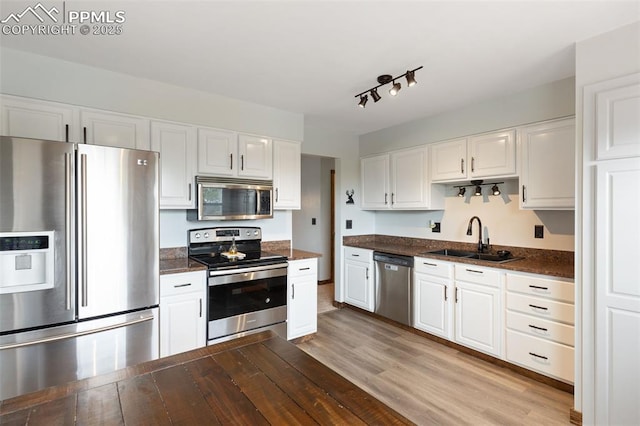 kitchen featuring a sink, appliances with stainless steel finishes, white cabinets, and wood finished floors