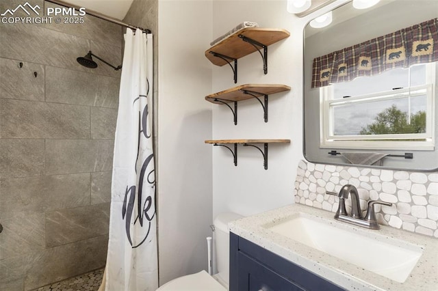 bathroom with vanity, toilet, tiled shower, and tasteful backsplash