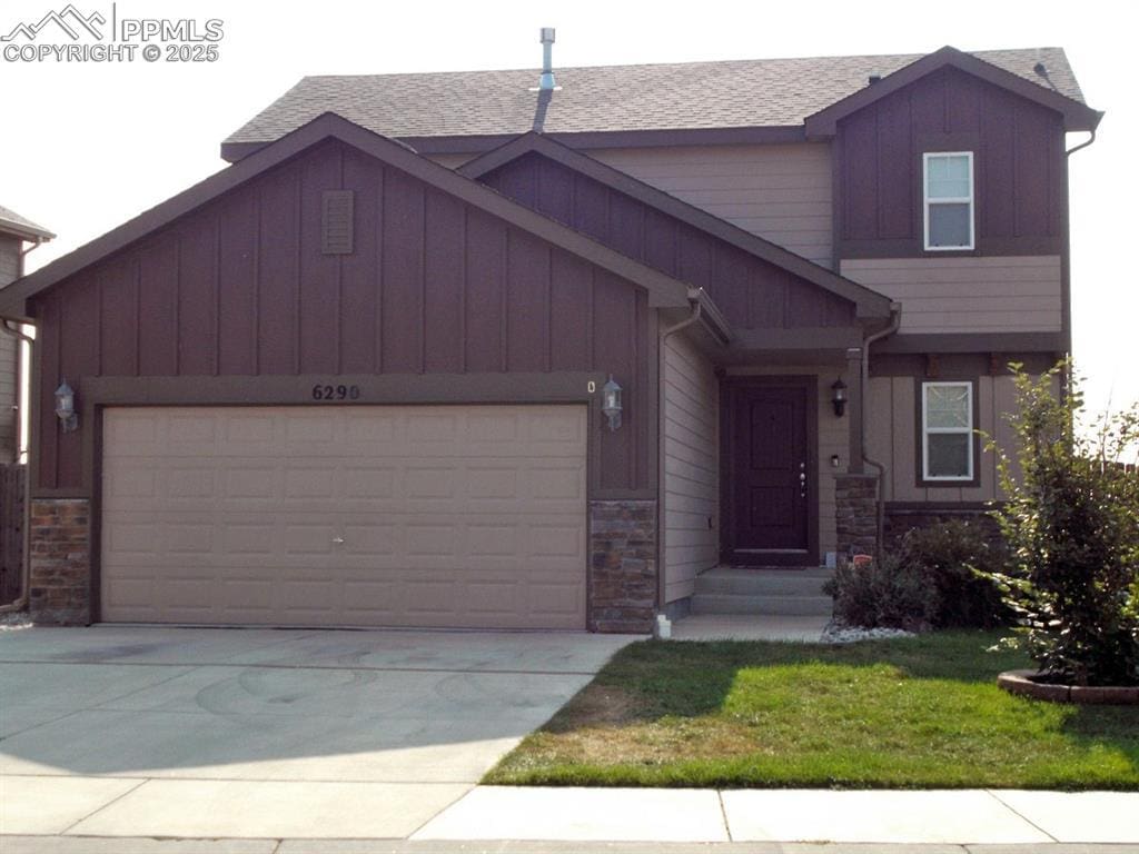 view of front of home with a garage, board and batten siding, and stone siding