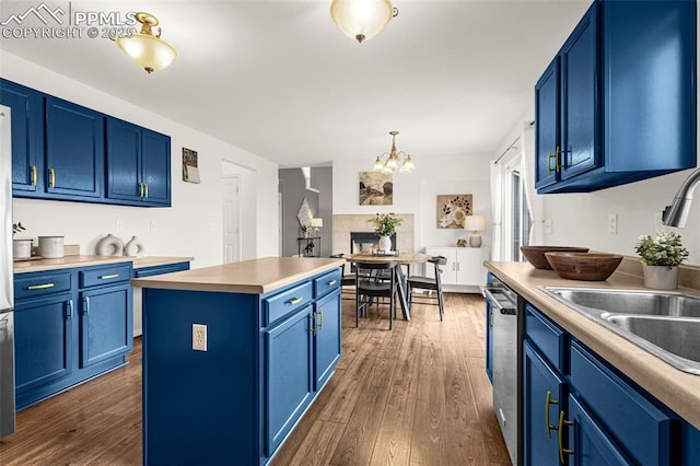 kitchen featuring blue cabinetry, a notable chandelier, a sink, and dark wood-type flooring